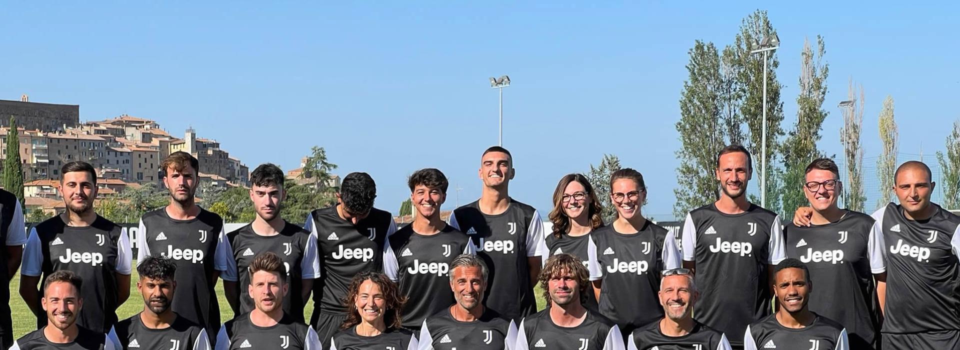 Squadra di calcio in maglia nera con sponsor Jeep, posa per foto di gruppo all'aperto.