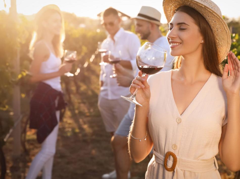 A group of friends tasting wine in a vineyard at sunset.