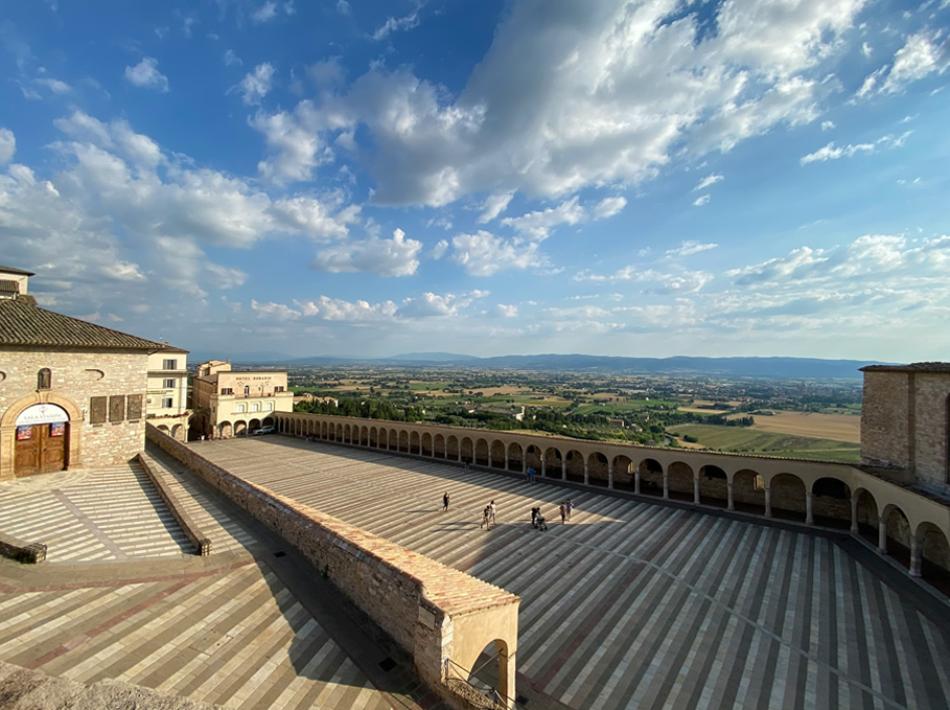 Panorama su un'ampia piazza con archi e vista sulla campagna.