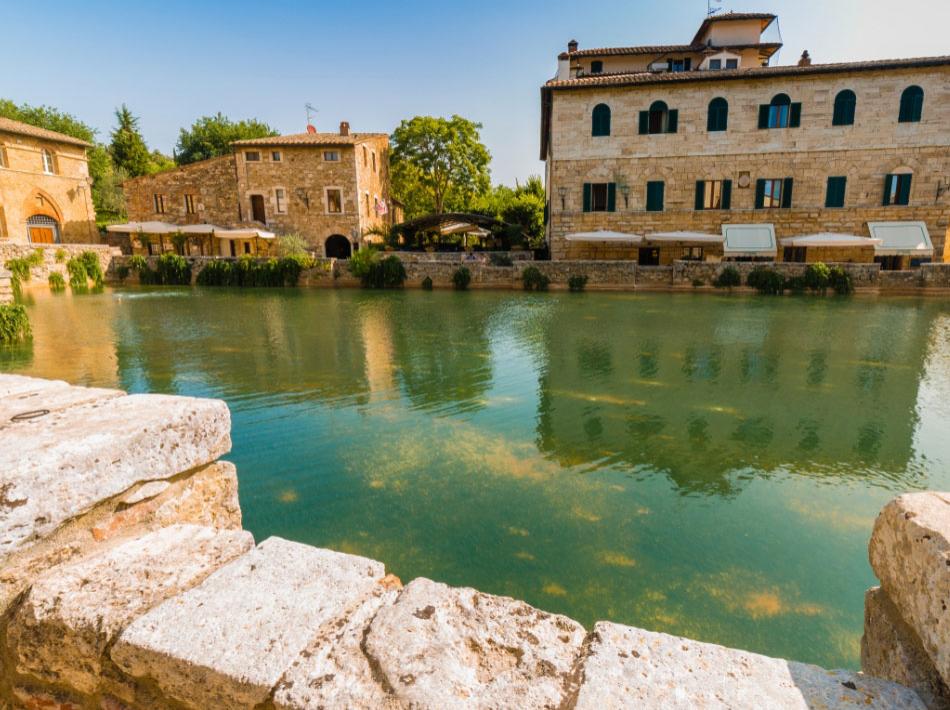Un pittoresco borgo con edifici storici e un laghetto tranquillo.