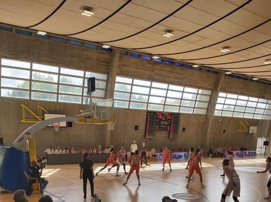 Partita di basket indoor con telecronisti e telecamere in palestra.
