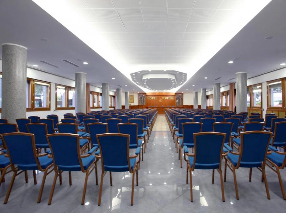 Sala conferenze spaziosa con sedie blu e illuminazione moderna.