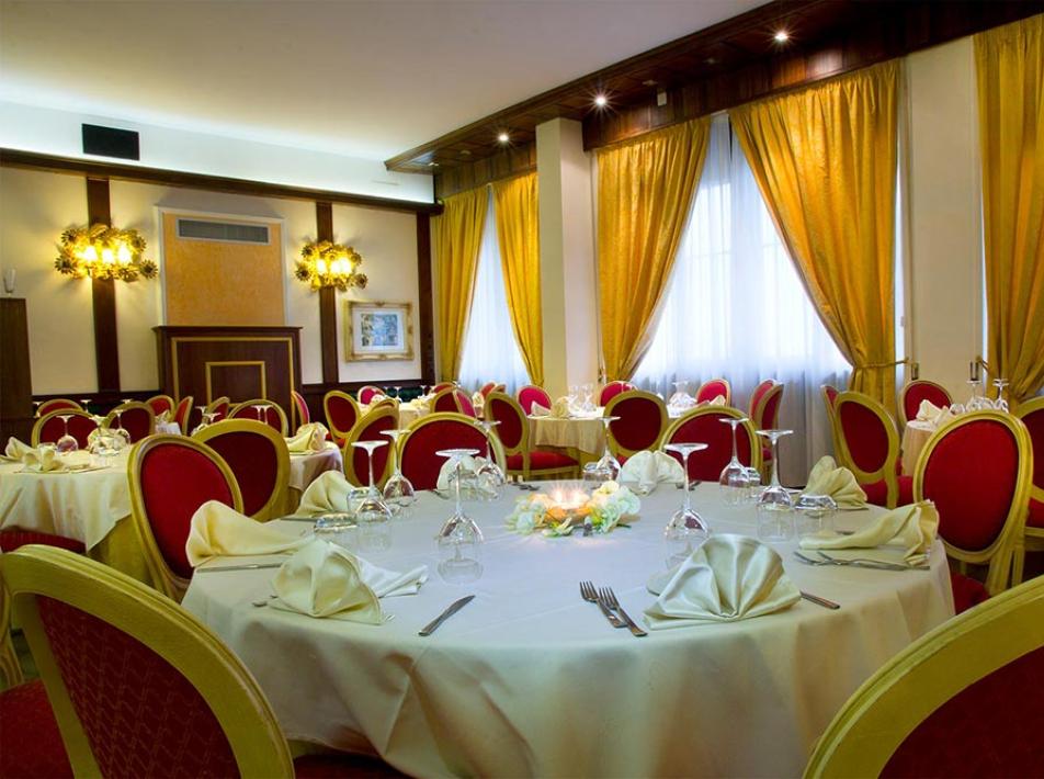 Sala da pranzo elegante con tavoli rotondi e sedie rosse.
