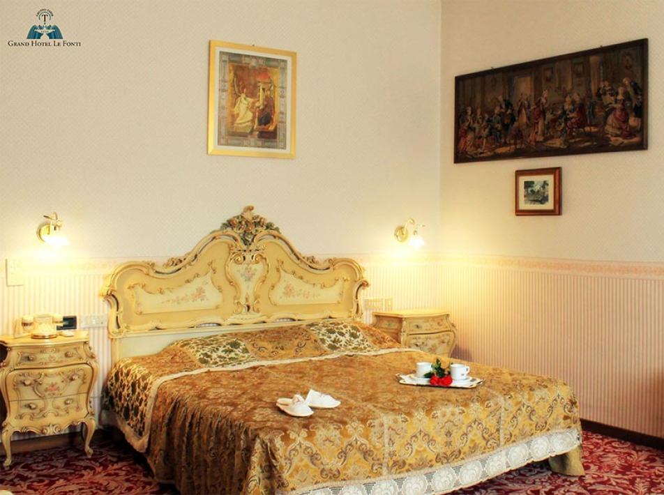 Camera elegante con letto matrimoniale, decorazioni classiche e dipinti alle pareti.