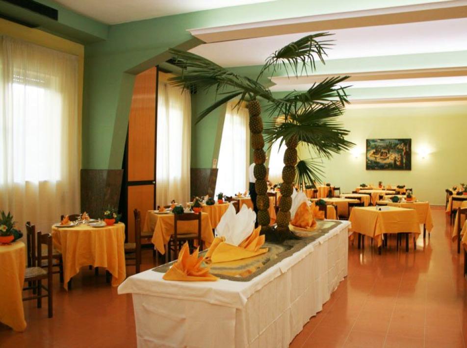 Ristorante elegante con tavoli apparecchiati e decorazioni tropicali al centro della sala.
